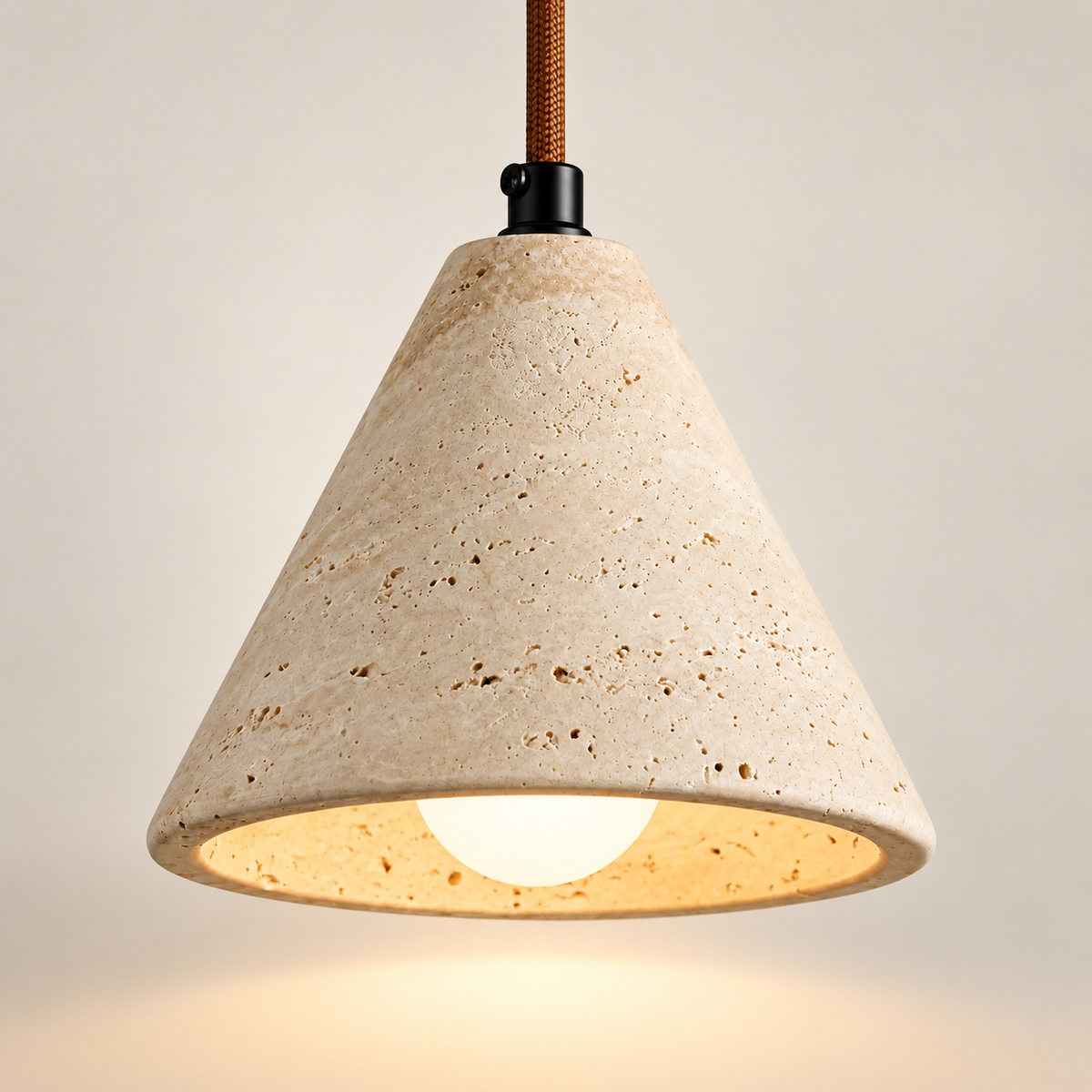 Ambra yellow travertine cone pendant light, lit, on a greige studio background