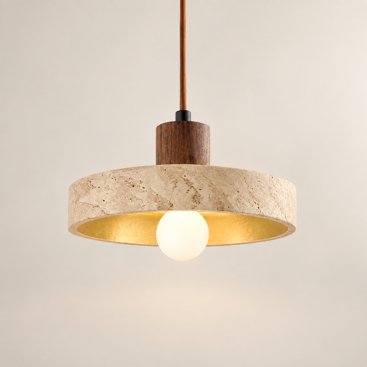Anela travertine and walnut pendant light, lit, on a greige studio background