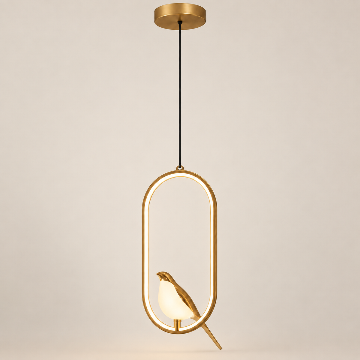 Aviora gold bird LED pendant light, lit, on a greige studio background