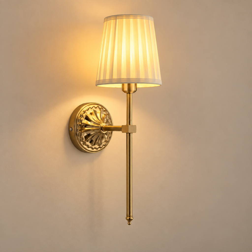 Beatrix cordless rechargeable wall light in antique gold with pleated shade, lit, on a greige wall
