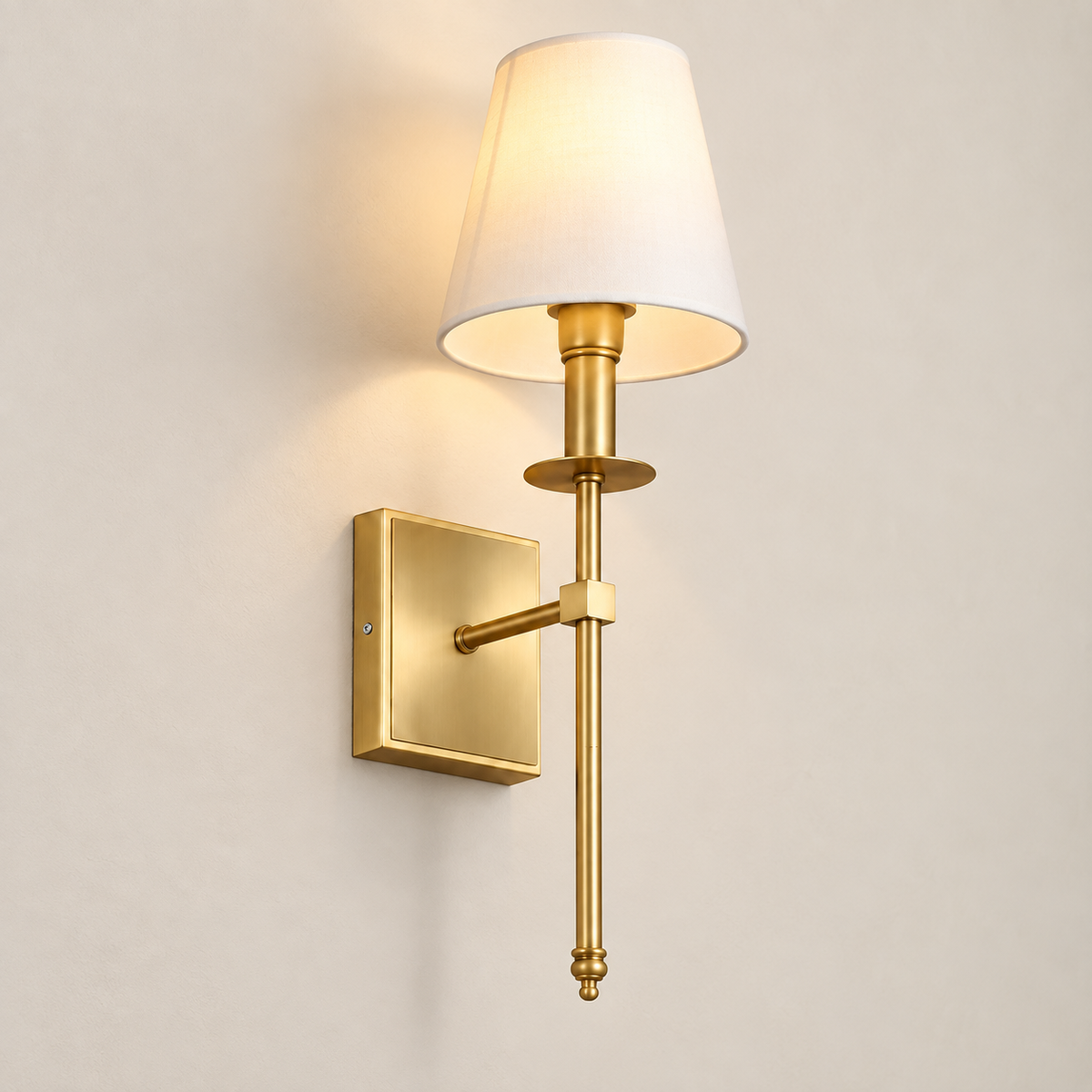 Clara fabric shade wall light with gold arm, lit, on a greige wall