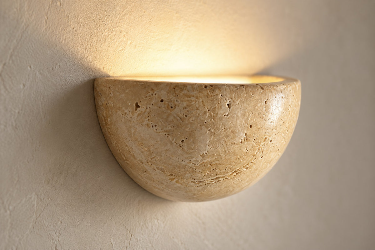 Close-up of the natural travertine texture of the Lunara half-moon wall light