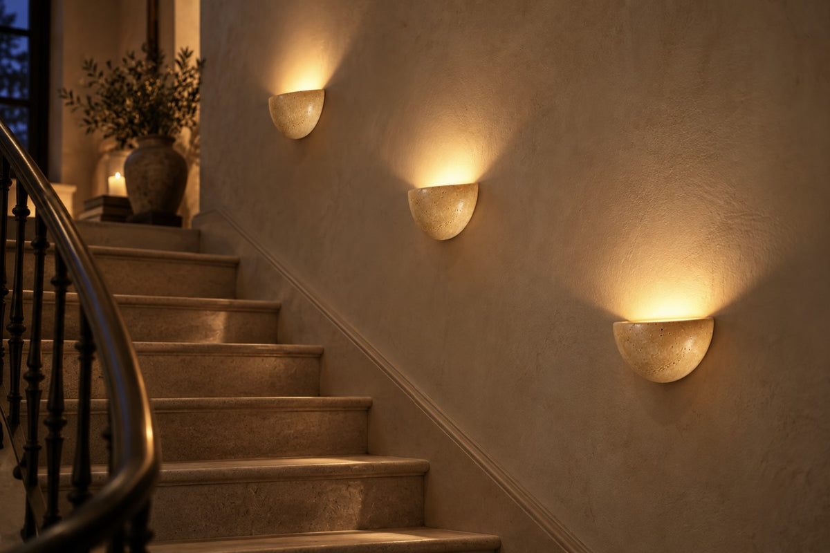 Three Lunara travertine wall lights glowing up a staircase wall at night