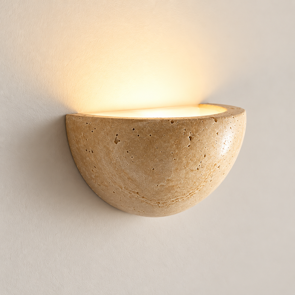 Lunara travertine half-moon wall light from a three-quarter angle, showing its curved stone bowl