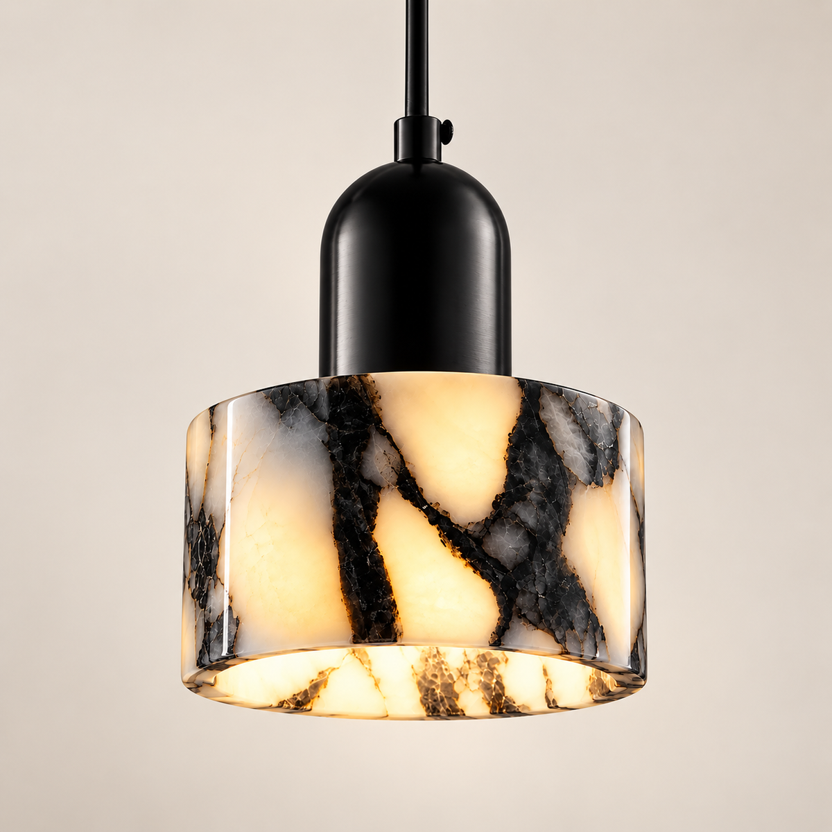Marra natural stone drum pendant light with black veining, lit, on a greige studio background