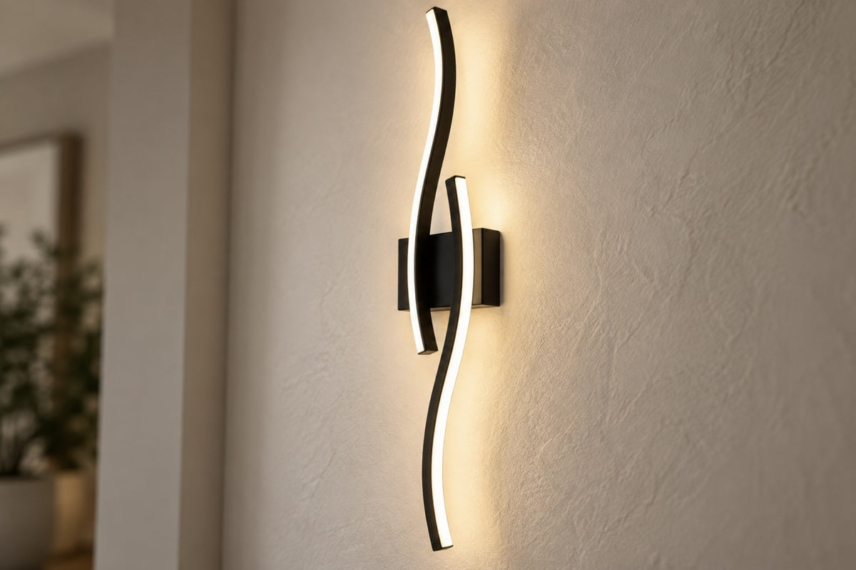 Close-up of the Onda black wave LED wall light glowing on a plaster wall