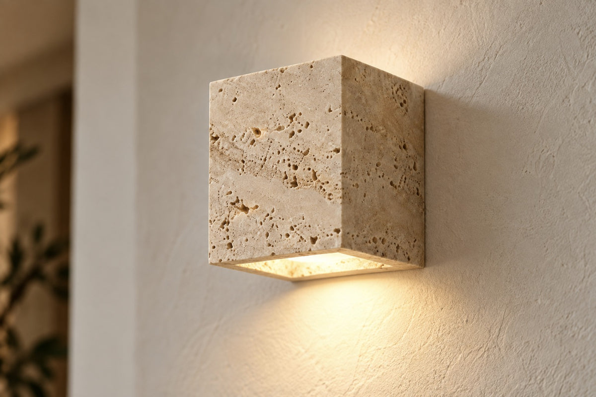 Close-up of the Petra travertine cube wall light and its natural pores, lit