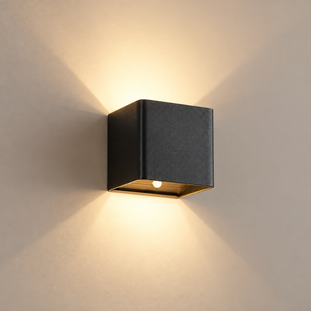 Quadra cordless rechargeable up-and-down cube wall light in matte black, lit, on a greige wall
