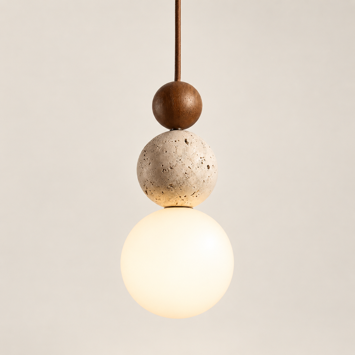 Terra walnut, travertine and frosted glass pendant light, lit, on a greige studio background